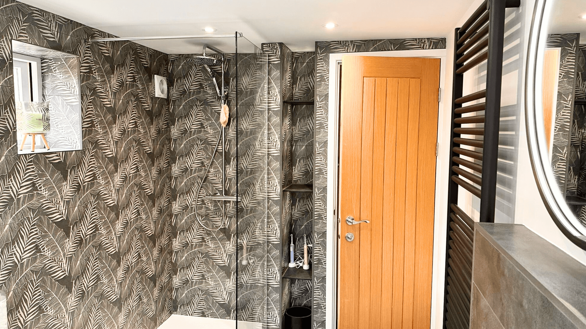 A bathroom with floral tiles and a walk in shower.